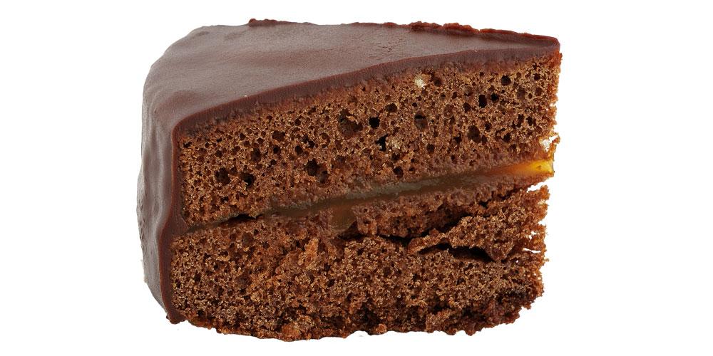 Sachertortenstück von der Seite vor weißem Hintergrund