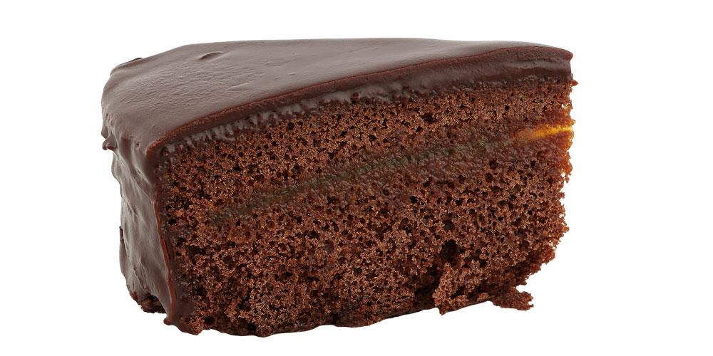 Sachertortenstück von der Seite vor weißem Hintergrund