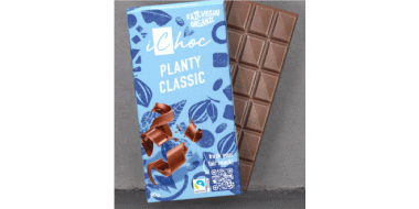 Eine Tafel iChoc „Planty Classic“ Schokolade. Die Verpackung ist blau mit braunen Schokoladenstücken und Blättermotiven. Es handelt sich um eine faire, vegane und biologische Schokolade. Neben der Verpackung ist die geöffnete Tafel mit rechteckigen Stücken sichtbar.