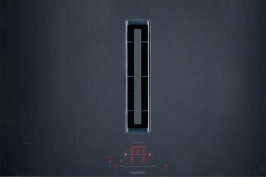 Induktionskochfeld mit integriertem Dunstabzug in der Mitte des grauen Kochfeldes