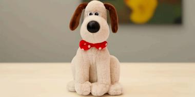 Heller Plüschhund mit Halsschleife und schwarzen Schlappohren