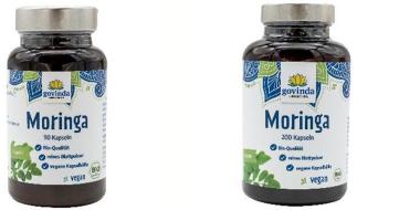Auf dem Bild stehen zwei dunkle Kunststoffdosen mit silberfarbenem Schraubverschluss. Beide tragen weiß-blaue Etiketten der Marke „Govinda“. Der linke Behälter enthält „Moringa – 90 Kapseln“, der rechte „Moringa – 200 Kapseln“. Auf den Etiketten sind grüne Blätter abgebildet sowie Hinweise wie „Bio-Qualität“, „vegan“ und „reines Blattpulver“.