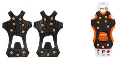 Das Bild zeigt zwei schwarze Gummi-Schneekrallen mit mehreren runden Metallspikes zur besseren Bodenhaftung. Rechts daneben ist die Produktverpackung abgebildet: eine orange-schwarze Schneekralle in einer weißen Kartonhülle mit dem Hinweis „Walk Traction“ und Symbolen zur Nutzung im Winter.