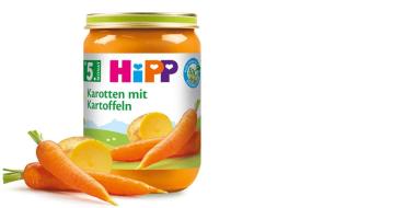 Das Bild zeigt ein Glas Babybrei der Marke HiPP mit der Aufschrift „Karotten mit Kartoffeln“, geeignet ab dem 5. Monat. Auf dem Etikett sind Karotten und Kartoffeln abgebildet, passend zum Inhalt. Vor dem Glas liegen frische Karotten und halbierte Kartoffeln.
