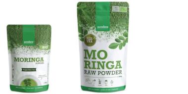 Das Bild zeigt zwei grüne Verpackungen für Moringa-Pulver. Links steht ein kleiner Beutel mit der Aufschrift „MORINGA POWDER“ und „BIO“, rechts ein größerer Beutel mit „MORINGA RAW POWDER“. Beide sind in Weiß und Grün gehalten, mit Blattmotiven und natürlichen Elementen gestaltet, was auf ein pflanzliches, gesundes Produkt hinweist.