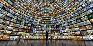 Eine Person steht vor einer riesigen geschwungenen Videowall, die einen gesamten Raum in der Breite und Höhe einnimmt.
