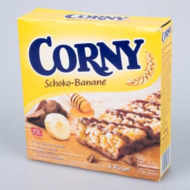 Corny Schoko-Banane: Auf der Verpackung sind ein Müsliriegel, eine Scheibe Banane, ein Stück Schokolade und ein Honiglöffel abgebildet. Bild: VKI.