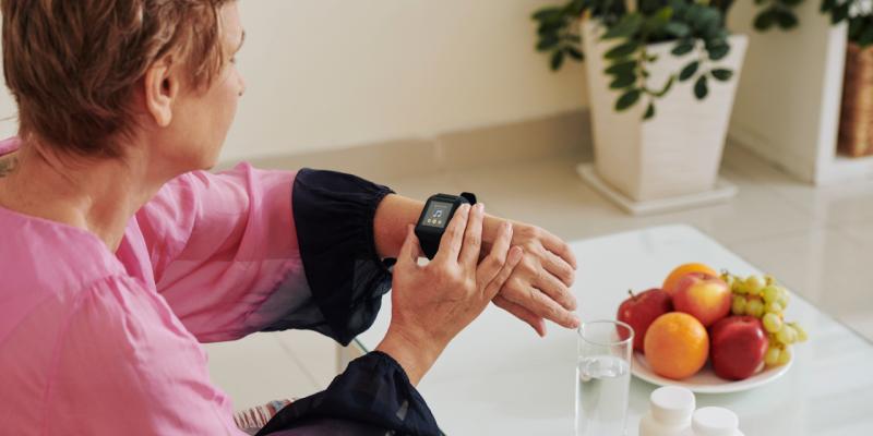 Smartwatches für Senioren: Diese Frau sieht auf eine, während sie am Tisch sitzt