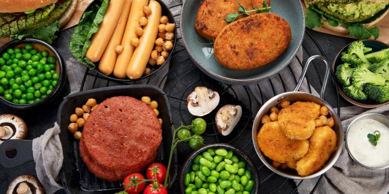 Fleischersatzprodukte in unterschiedlicher Form von Würstel über Burgerpatties zu Nuggets am Tisch liegend
