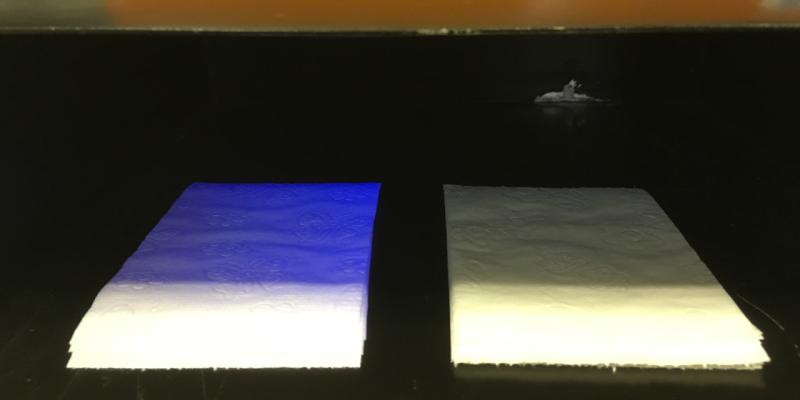 Zwei Klopapiere unter UV-Lampe, eines reflektiert blau