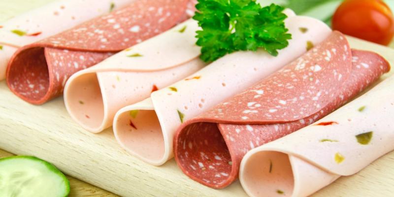 Vegetarische Salami und pikante Extrawurst in Scheiben und gerollt nebeneinander auf Holzbrett