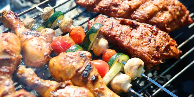 Fleisch und Gemüsespieße liegen auf einem Grillrost