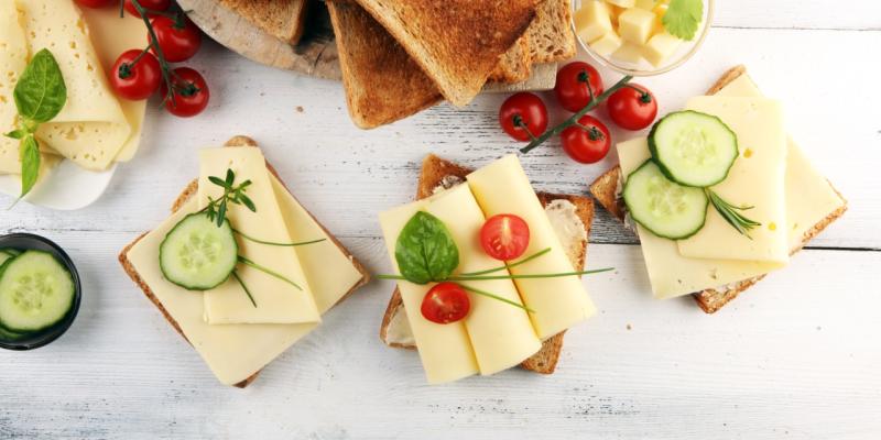 Käse in Scheiben auf Toastbrot mit Gurken und Tomaten garniert