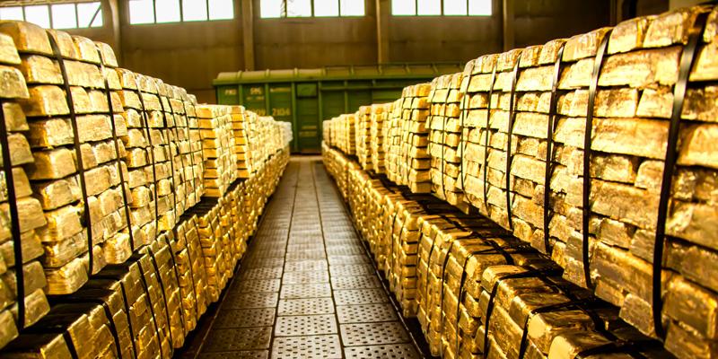 Gold kaufen - Edelmetall als Anlage: Riesige Menge an Goldbarren geschlichtet in einer Halle