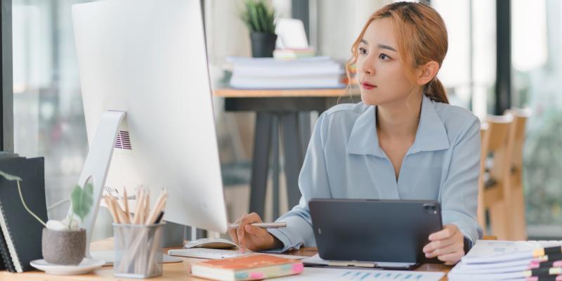 Frau arbeitet mit Tablet und Desktop