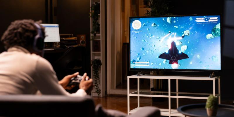 Ein Mann mit Dreadlocks sitzt vor einem Fernseher und spielt ein Computerspiel.