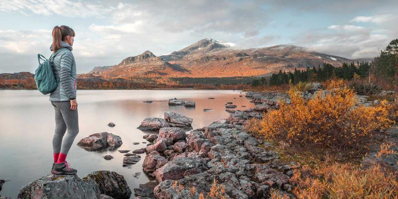 Frau in Wanderausrüstung vor einem See in Lappland