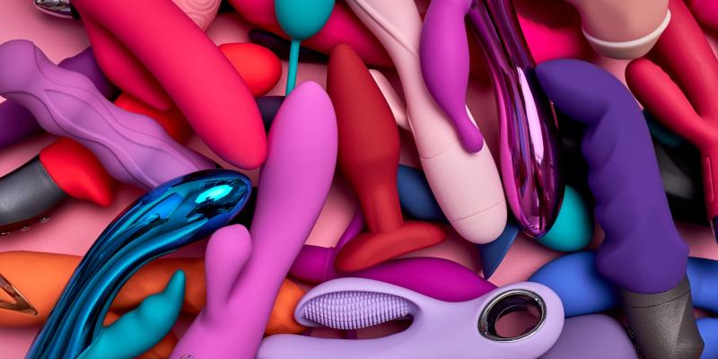 Mehrere Dildos und Vibratoren liegen nebeneinander und übereinander. 