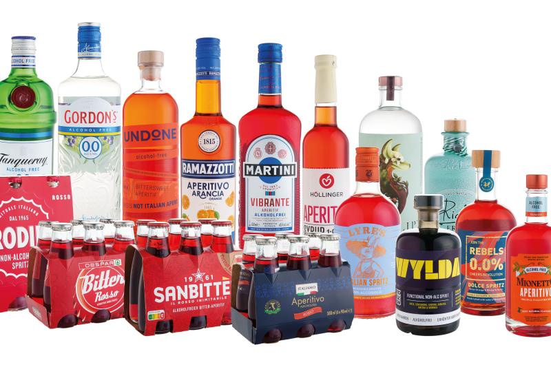 Alkoholfreie Aperitifs und ein Getränk mit besonderer Wirkung, überwiegend orange Flüssigkeiten in Flaschen, einige Flaschen in Gebinden.