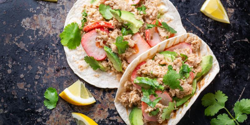 Auf schwarzem Untergrund zwei Taco-Fladen mit veganen Fischprodukten belegt