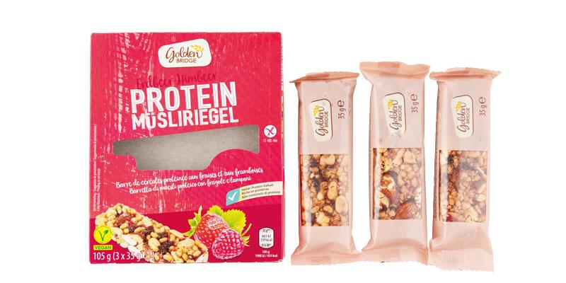 Leere Protein Müsliriegelpackung. Packung rot mit weißer Schrift, daneben drei Müsliriegel.