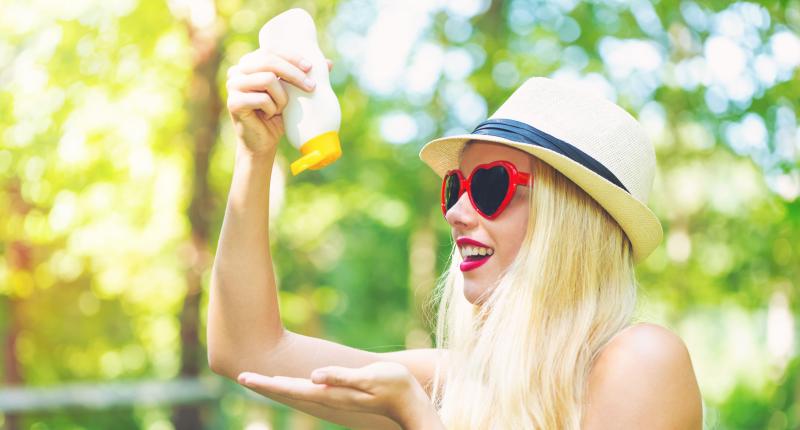 Junge Frau mit Sonnenbrille und Sonnencremetube 