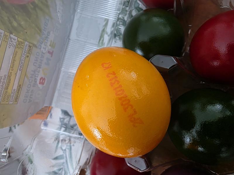 Auf einem orange gefärbten, gekochten Ei ist die Herkunftskennzeichnung PL zu sehen.