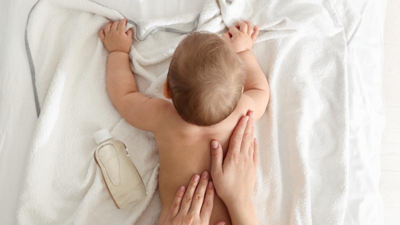 Baby wird am Rücken eingeölt