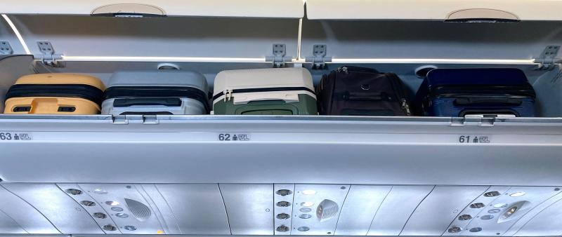 offenes, mit vielen kleinen Koffern gefülltes Überkopffach in Flugzeug