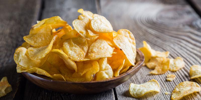dunkle Schale voll mit Kartoffelchips auf dunklem Holztisch