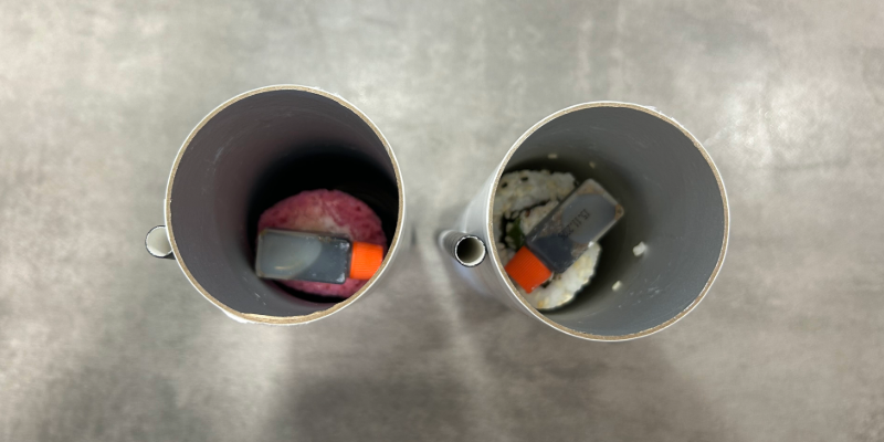 Blick von oben in zwei aufrecht stehende „Sushi 4You"-Tuben, auf dem Sushi liegt noch ein kleines Fläschchen Sojasauce. 
