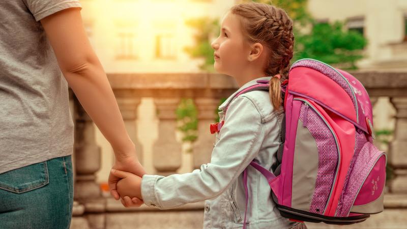 Mädchen mit rosa Schultasche Hand in Hand mit Mama