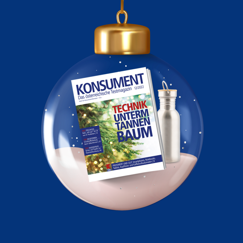 KONSUMENT-Ausgabe 12/2022 in einer Weihnachtskugel, wo es schneit. Hinter dem Heft ist eine silberne Edelstahl-Trinkflasche.